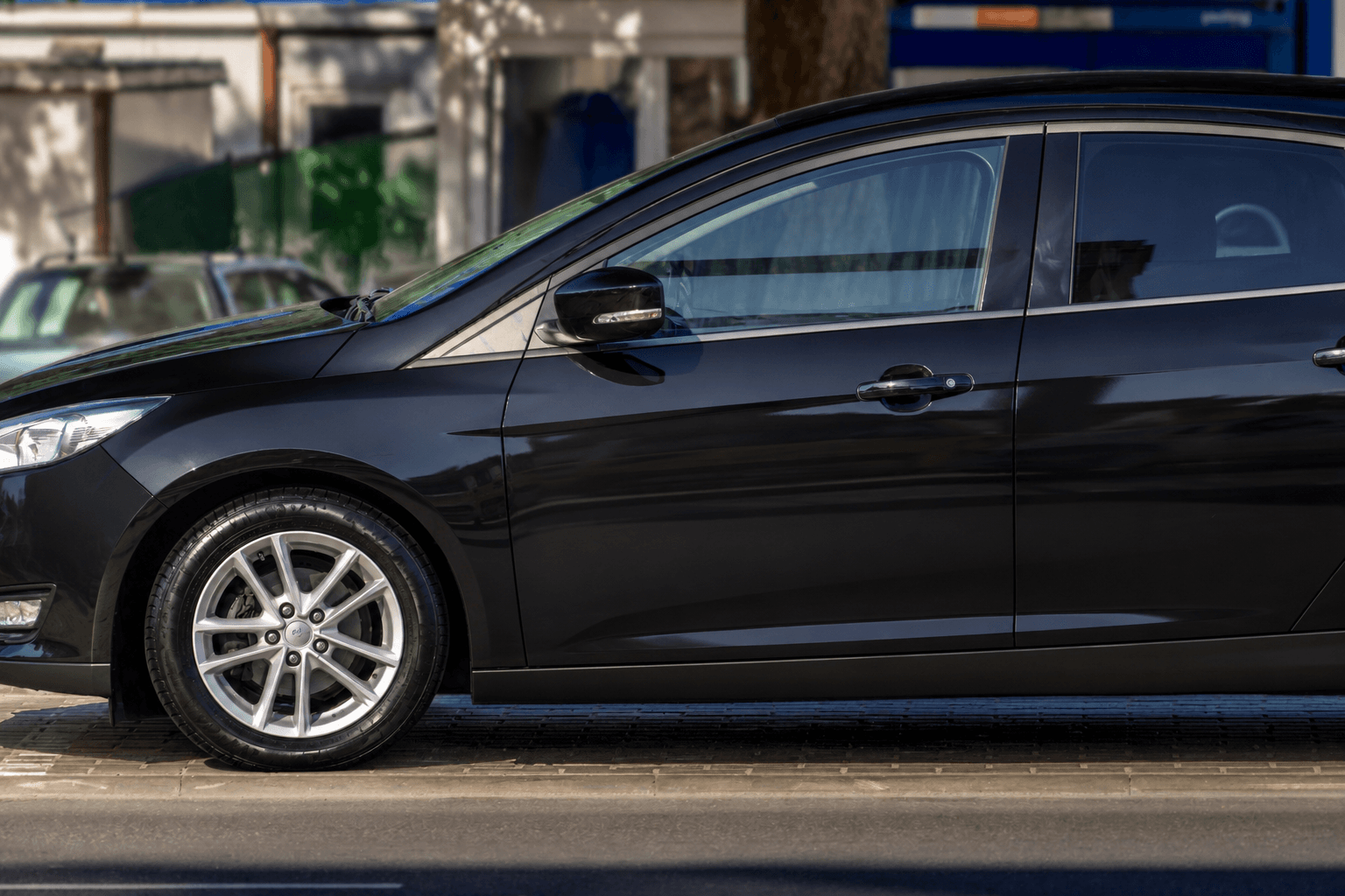 The same black sedan after detailing, cleaned and restored to a glossy finish.